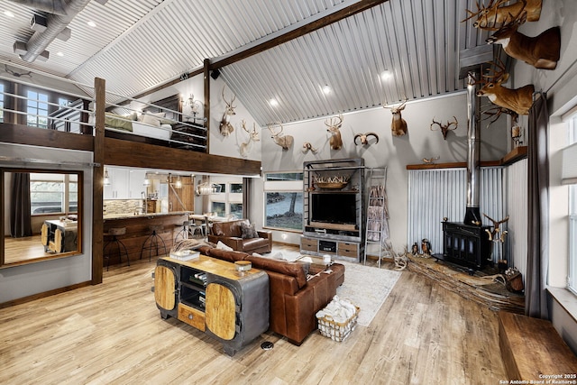 living room with a wood stove, wooden ceiling, high vaulted ceiling, and light hardwood / wood-style flooring