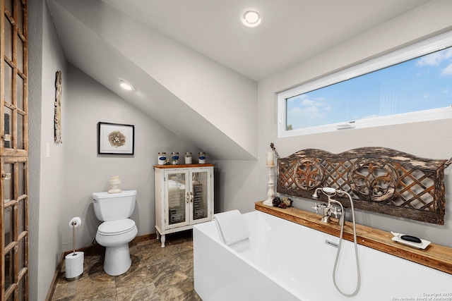 bathroom with toilet, vaulted ceiling, and a tub to relax in