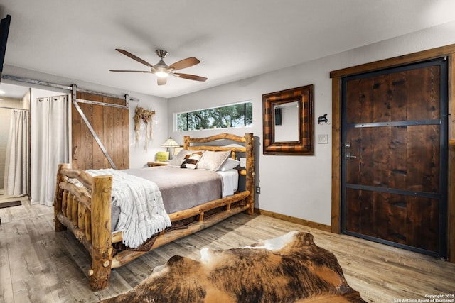 bedroom with hardwood / wood-style flooring, a barn door, and ceiling fan