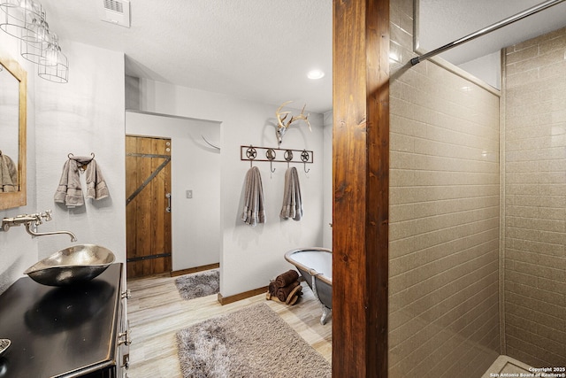 bathroom featuring independent shower and bath, sink, hardwood / wood-style floors, and a textured ceiling