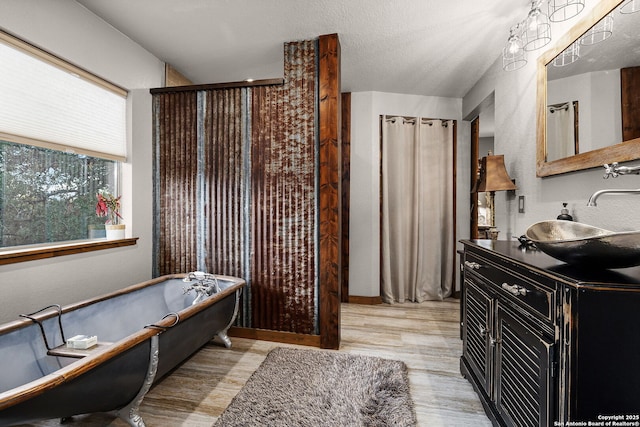 bathroom with wood-type flooring, separate shower and tub, vanity, and a textured ceiling