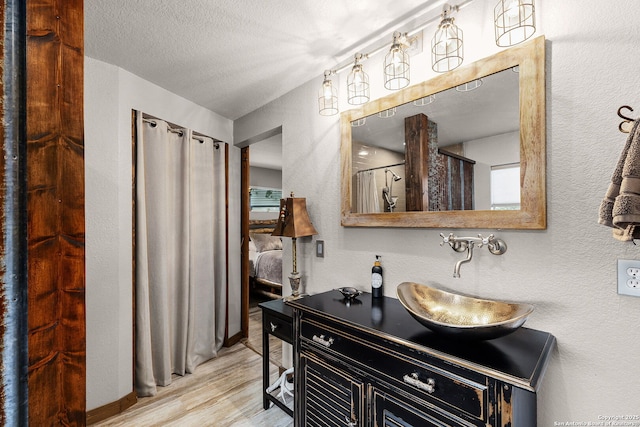 bathroom with hardwood / wood-style flooring, vanity, walk in shower, and a textured ceiling