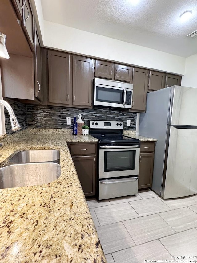 kitchen with tasteful backsplash, appliances with stainless steel finishes, sink, and dark brown cabinets