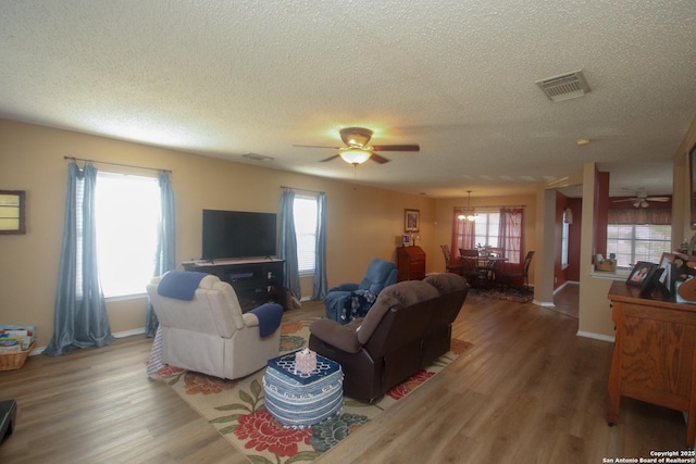 living room with hardwood / wood-style flooring, ceiling fan, and a textured ceiling