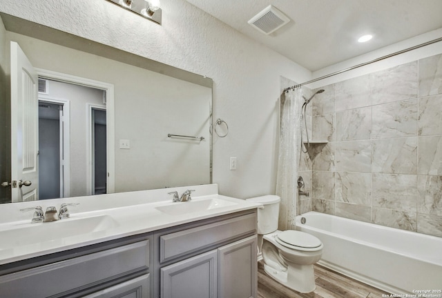 full bathroom with vanity, wood-type flooring, toilet, and tiled shower / bath