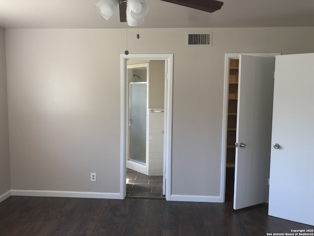 unfurnished bedroom with dark wood-type flooring, connected bathroom, and ceiling fan