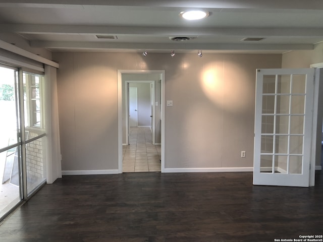 empty room featuring beamed ceiling and dark hardwood / wood-style flooring