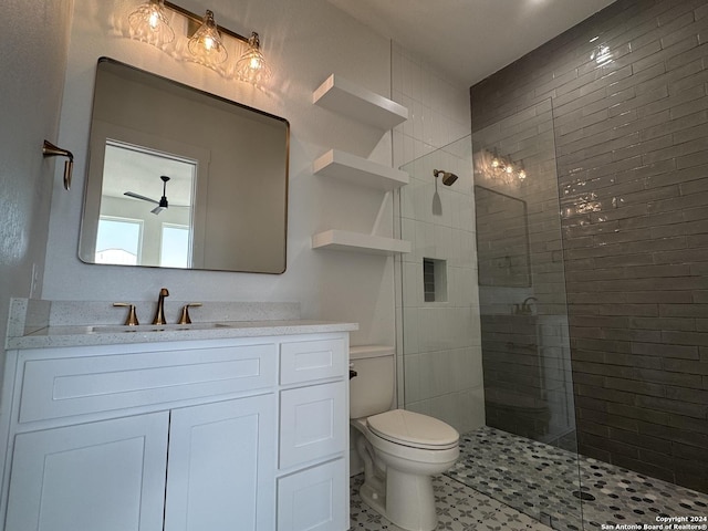 bathroom featuring vanity, a tile shower, and toilet