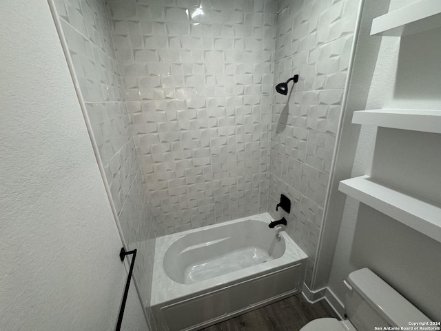 bathroom with tiled shower / bath, wood-type flooring, and toilet