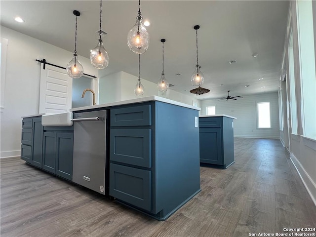 kitchen with dark wood-type flooring, a barn door, hanging light fixtures, and a center island with sink