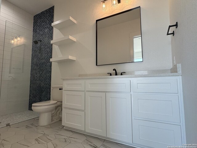 bathroom featuring vanity, tiled shower, and toilet