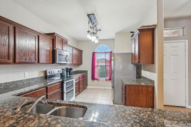 kitchen with pendant lighting, sink, light tile patterned floors, appliances with stainless steel finishes, and a textured ceiling