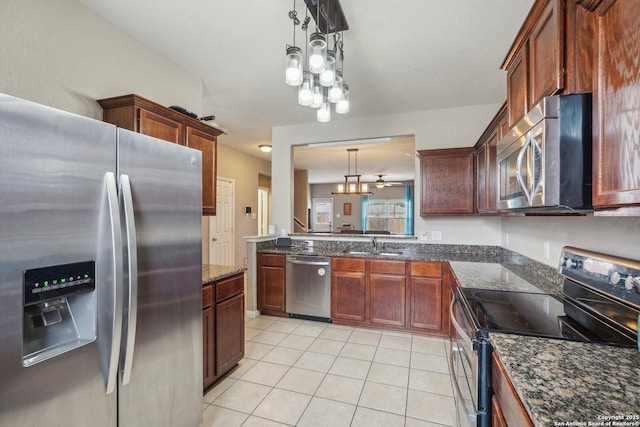 kitchen featuring sink, decorative light fixtures, dark stone countertops, light tile patterned floors, and stainless steel appliances