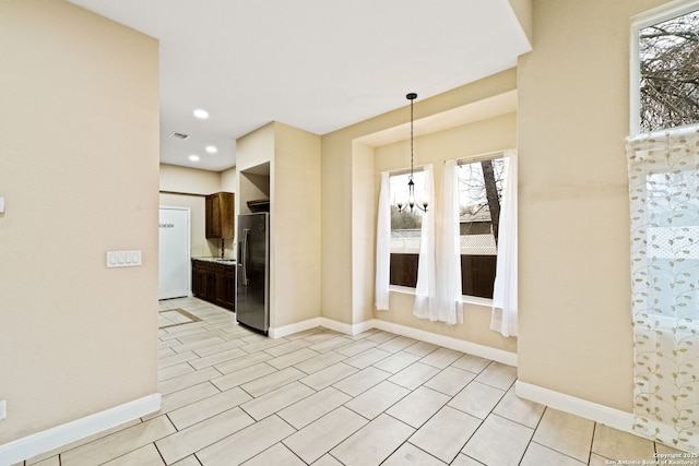 kitchen with an inviting chandelier, pendant lighting, stainless steel fridge, and dark brown cabinetry