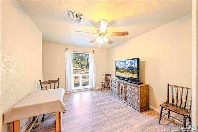 sitting room featuring ceiling fan, light hardwood / wood-style flooring, and a textured ceiling