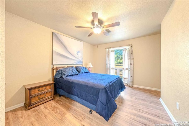 bedroom with access to outside, a textured ceiling, and light hardwood / wood-style floors