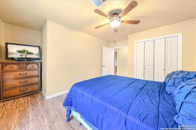 bedroom with a closet, a textured ceiling, ceiling fan, and light hardwood / wood-style flooring