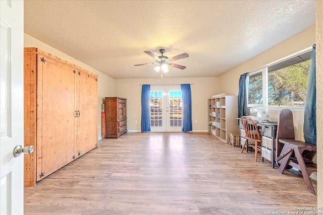 office space with french doors, ceiling fan, light hardwood / wood-style flooring, and a textured ceiling