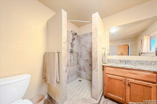 bathroom featuring vanity, tiled shower, and toilet