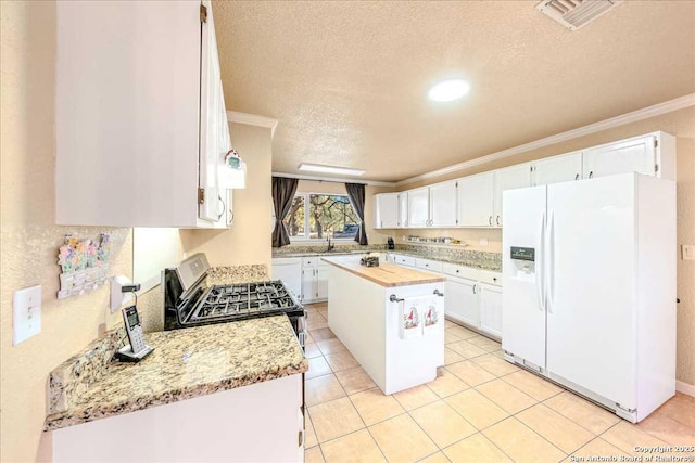 kitchen with white cabinetry, light stone counters, a center island, ornamental molding, and white fridge with ice dispenser