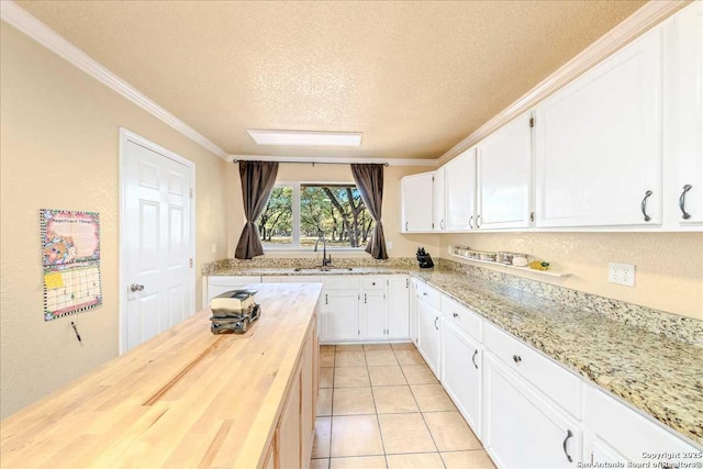 kitchen featuring wood counters, sink, a textured ceiling, and white cabinets