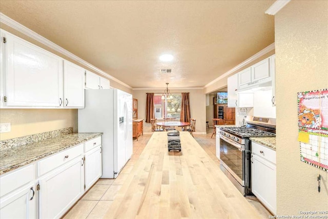 kitchen featuring hanging light fixtures, gas stove, white refrigerator with ice dispenser, and white cabinetry