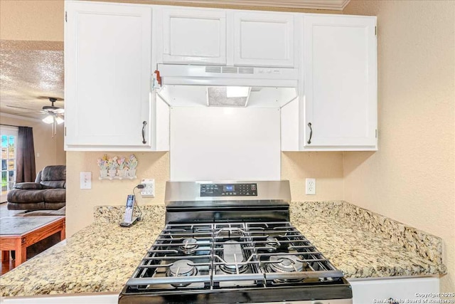 kitchen with white cabinetry, light stone counters, stainless steel gas range oven, and ceiling fan