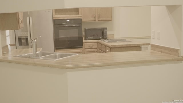 kitchen with light brown cabinetry, sink, and black appliances