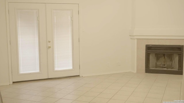 unfurnished living room with light tile patterned floors, a fireplace, and french doors