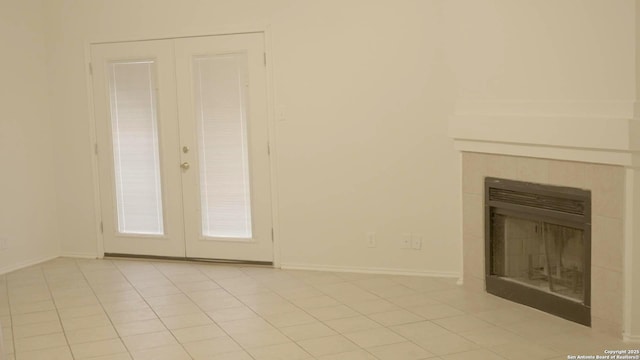 unfurnished living room featuring light tile patterned floors, a fireplace, and french doors