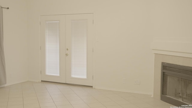 interior space with light tile patterned floors, a fireplace, and french doors