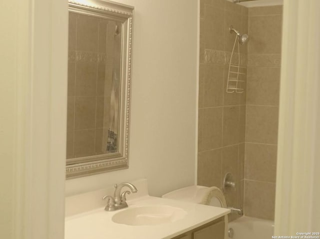 full bathroom featuring vanity, tiled shower / bath combo, and toilet