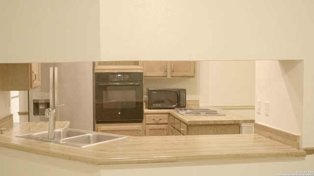 kitchen featuring sink, light brown cabinetry, and black appliances