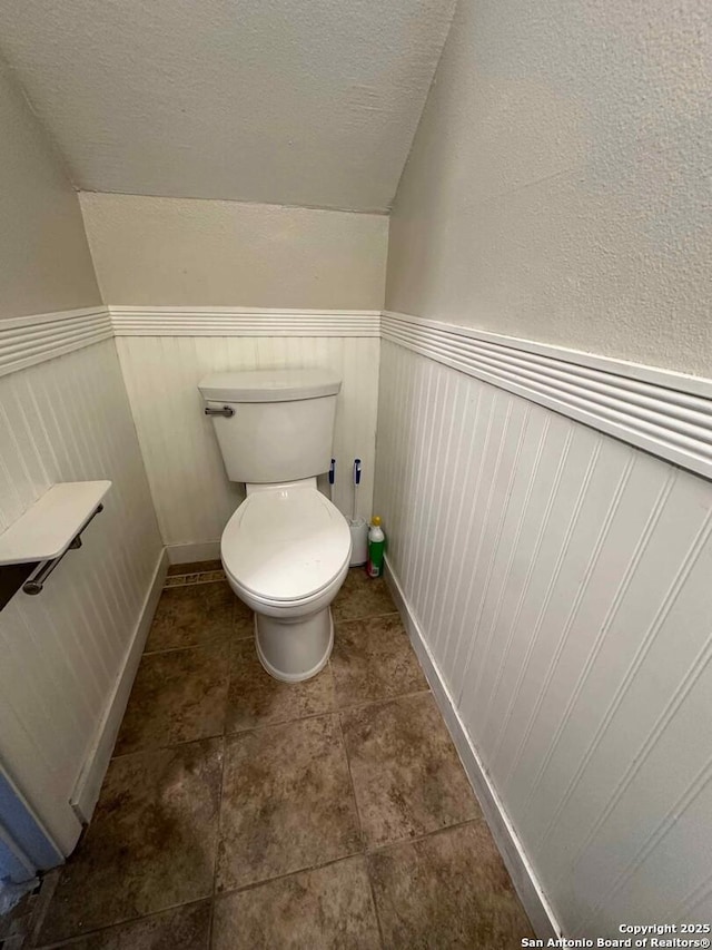 bathroom with lofted ceiling, a textured ceiling, and toilet