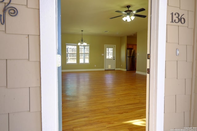 interior space with wood-type flooring and ceiling fan with notable chandelier