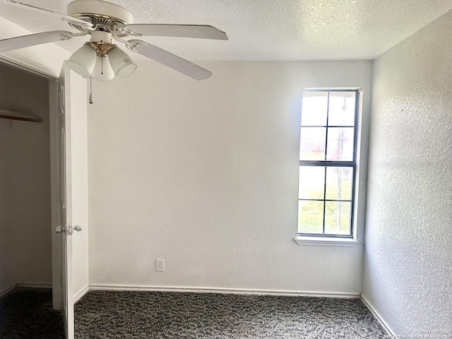 empty room with a healthy amount of sunlight, dark carpet, and a textured ceiling