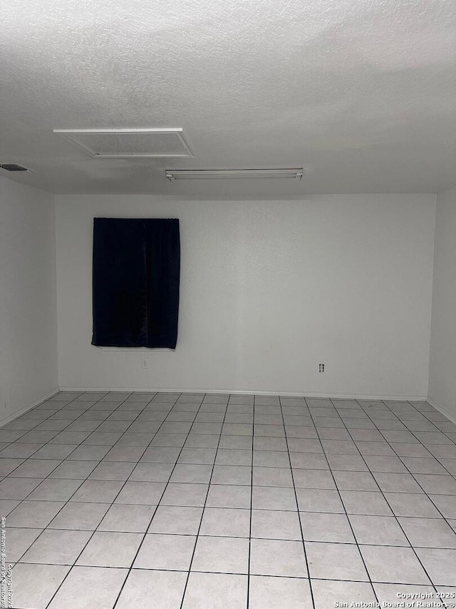 tiled empty room featuring a textured ceiling