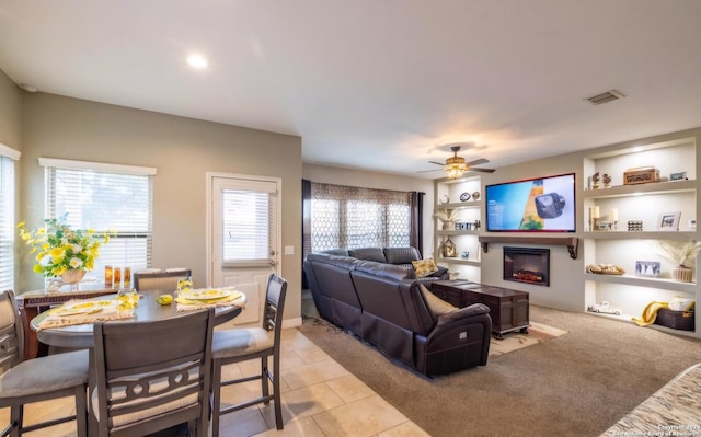 tiled living room featuring built in features and ceiling fan