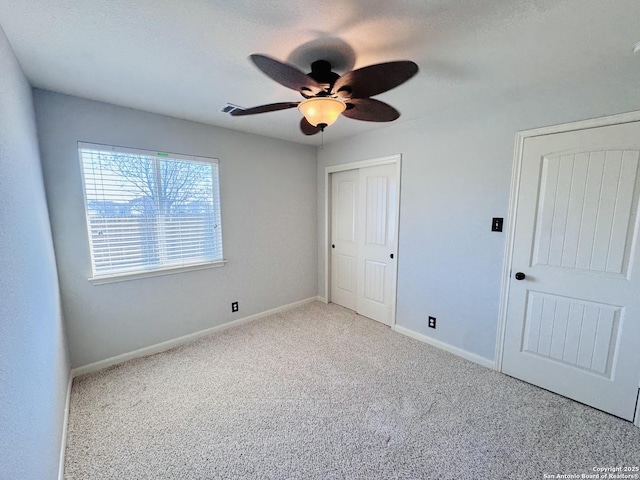 unfurnished bedroom featuring light carpet, a textured ceiling, a closet, and ceiling fan