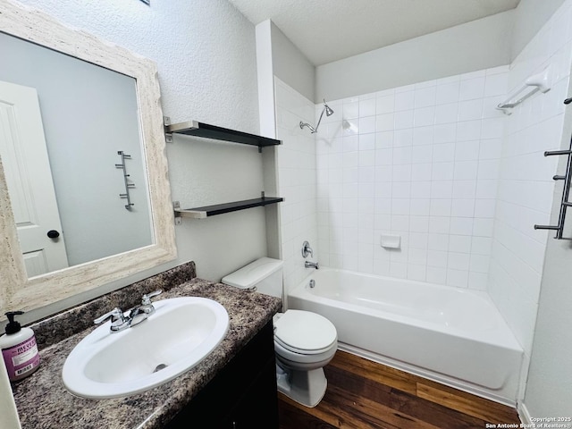 full bathroom with toilet, tiled shower / bath, a textured ceiling, vanity, and hardwood / wood-style flooring