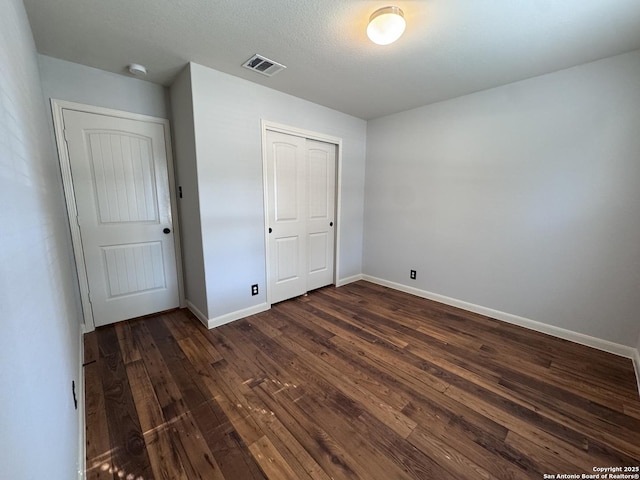 unfurnished bedroom featuring dark hardwood / wood-style floors and a closet