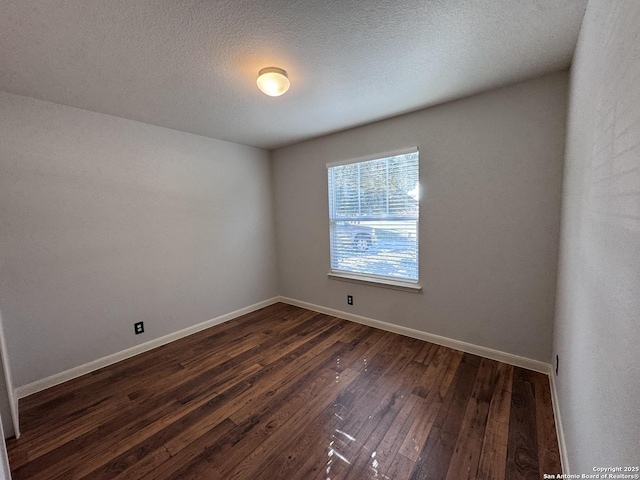 empty room featuring dark hardwood / wood-style floors and a textured ceiling