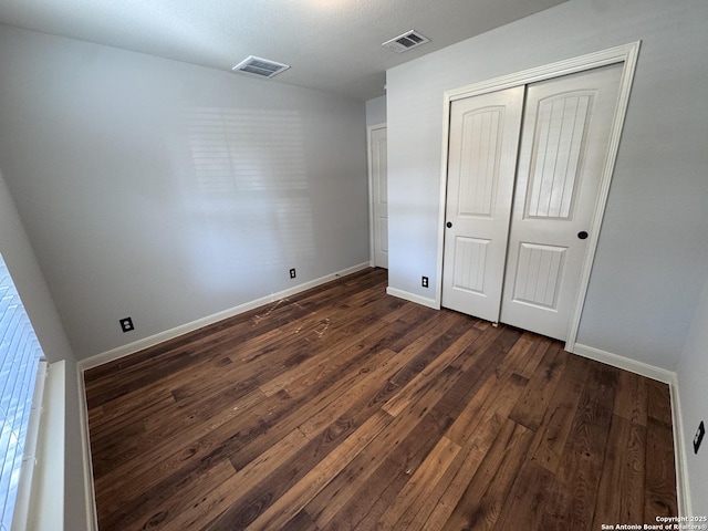 unfurnished bedroom featuring a closet and dark hardwood / wood-style floors