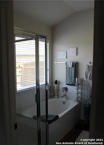 bathroom with independent shower and bath and lofted ceiling