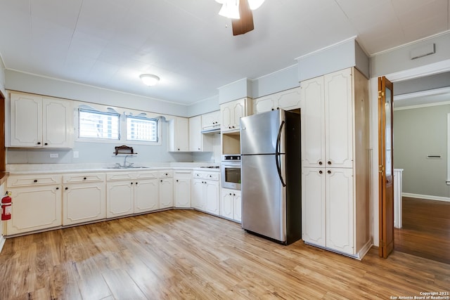 kitchen with appliances with stainless steel finishes, sink, white cabinets, and light hardwood / wood-style flooring