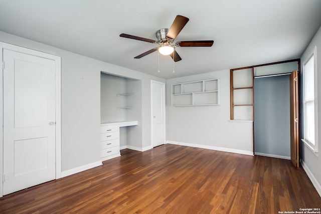 unfurnished bedroom featuring dark hardwood / wood-style floors, built in desk, and ceiling fan