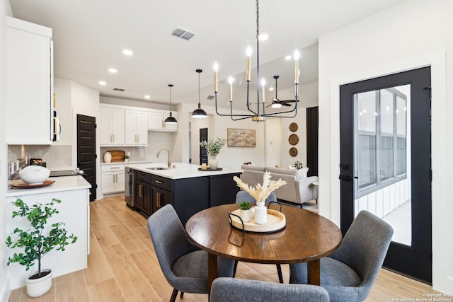 dining area with sink, an inviting chandelier, and light wood-type flooring