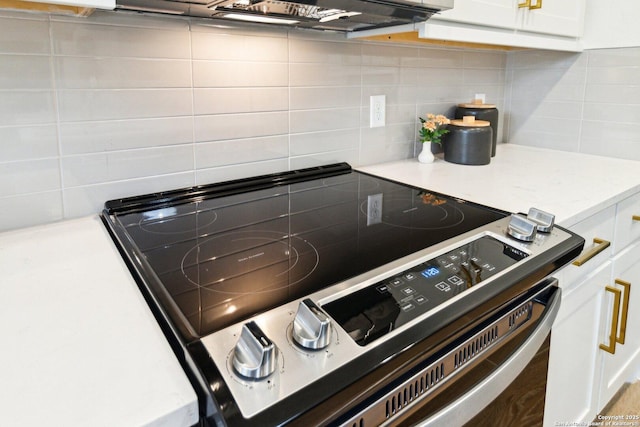 details featuring decorative backsplash, white cabinets, and stainless steel range with electric stovetop