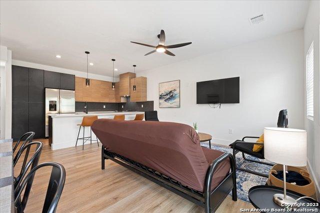 living room featuring ceiling fan, sink, and light hardwood / wood-style floors