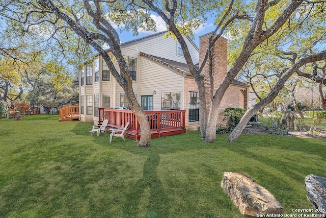 rear view of property with a wooden deck and a lawn